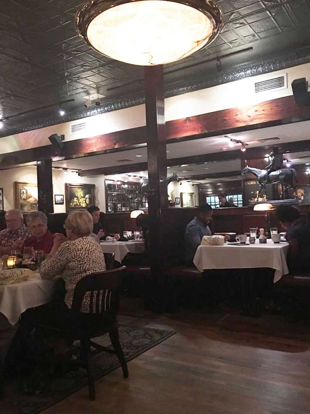 Cozy restaurant interior with diners enjoying meals at tables in an elegant setting.