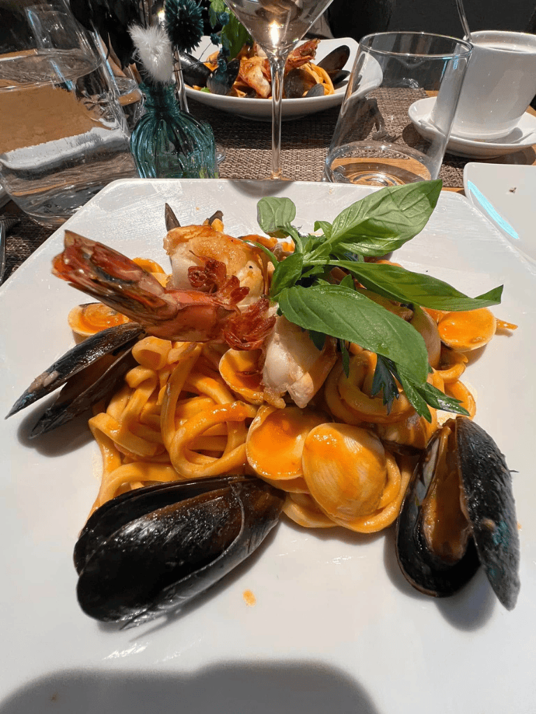 Seafood pasta with mussels, shrimp, and fresh basil on a white plate, perfect Italian cuisine.
