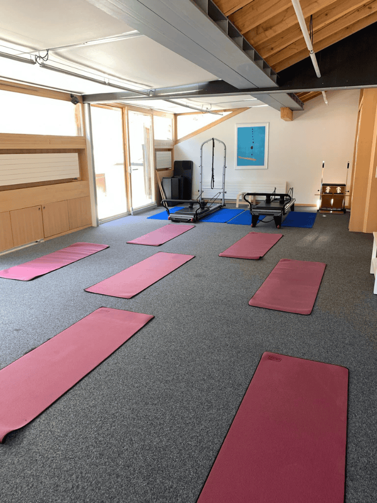 Yoga mats and Pilates equipment in a bright, airy fitness studio with natural light and modern wooden accents.