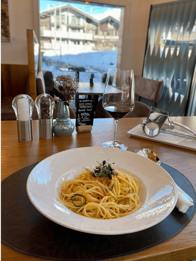 - Fresh pasta dish served with herbs and vegetables in a cozy restaurant setting.