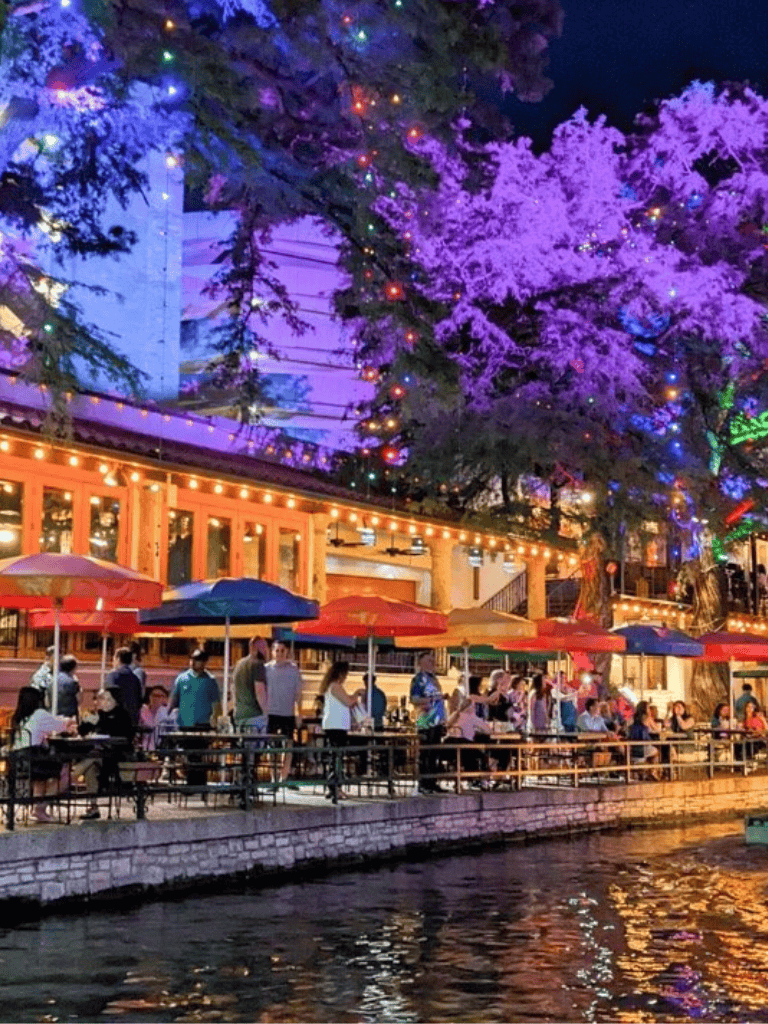 Colorful outdoor dining area by the waterfront with vibrant lights and night sky, ideal for leisure and relaxation.