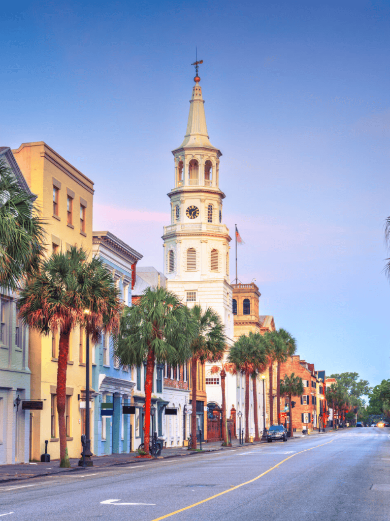 Colorful historic Charleston architecture with iconic church steeple and palm trees.