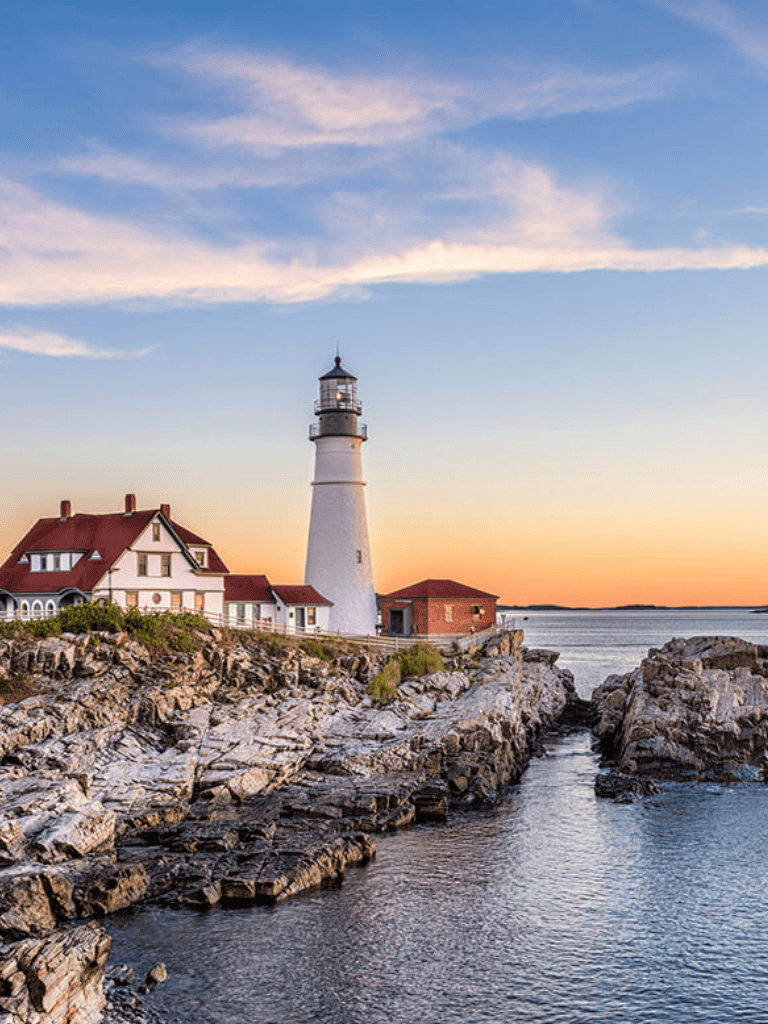 Lighthouse by rocky shoreline at sunset, scenic coastal view, guiding navigation, questfordirections.