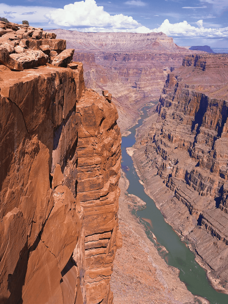 Vast Grand Canyon with layered red rock cliffs and winding Colorado River below.