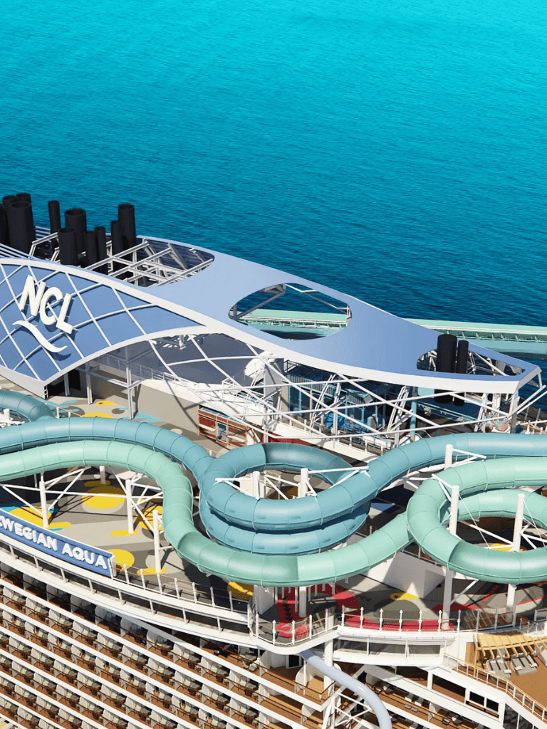 Thrilling water slides on cruise ship Norwegian Aqua with ocean view in the background.