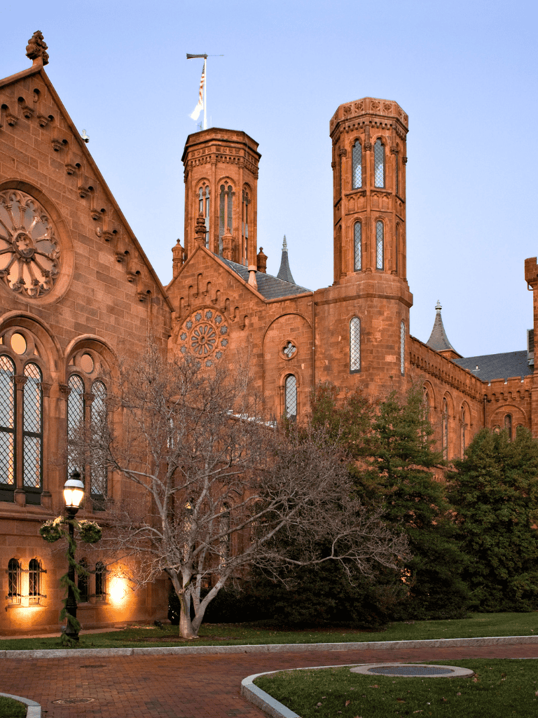 Red brick historic church with clock tower and Gothic windows during evening.