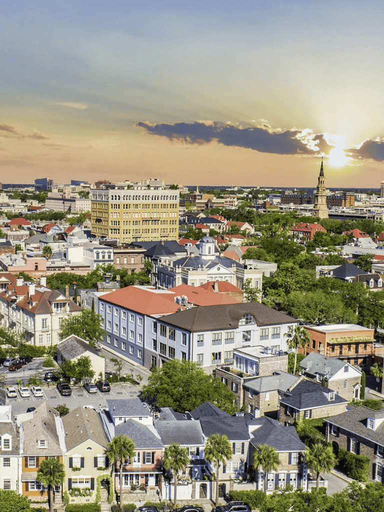 Colorful cityscape view of downtown with historic buildings, lush trees, and sunset sky in the background, showcasing urban environment.
