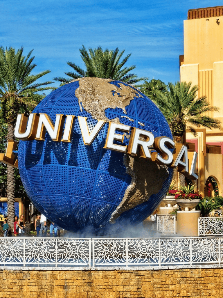 Vast blue Universal Studios globe at theme park entrance with palm trees in background.