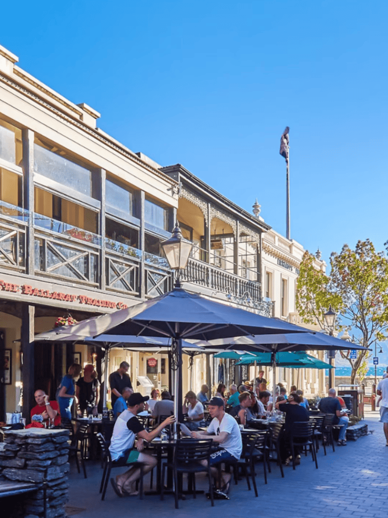 Outdoor dining at popular restaurant on bustling street in a charming waterfront town.