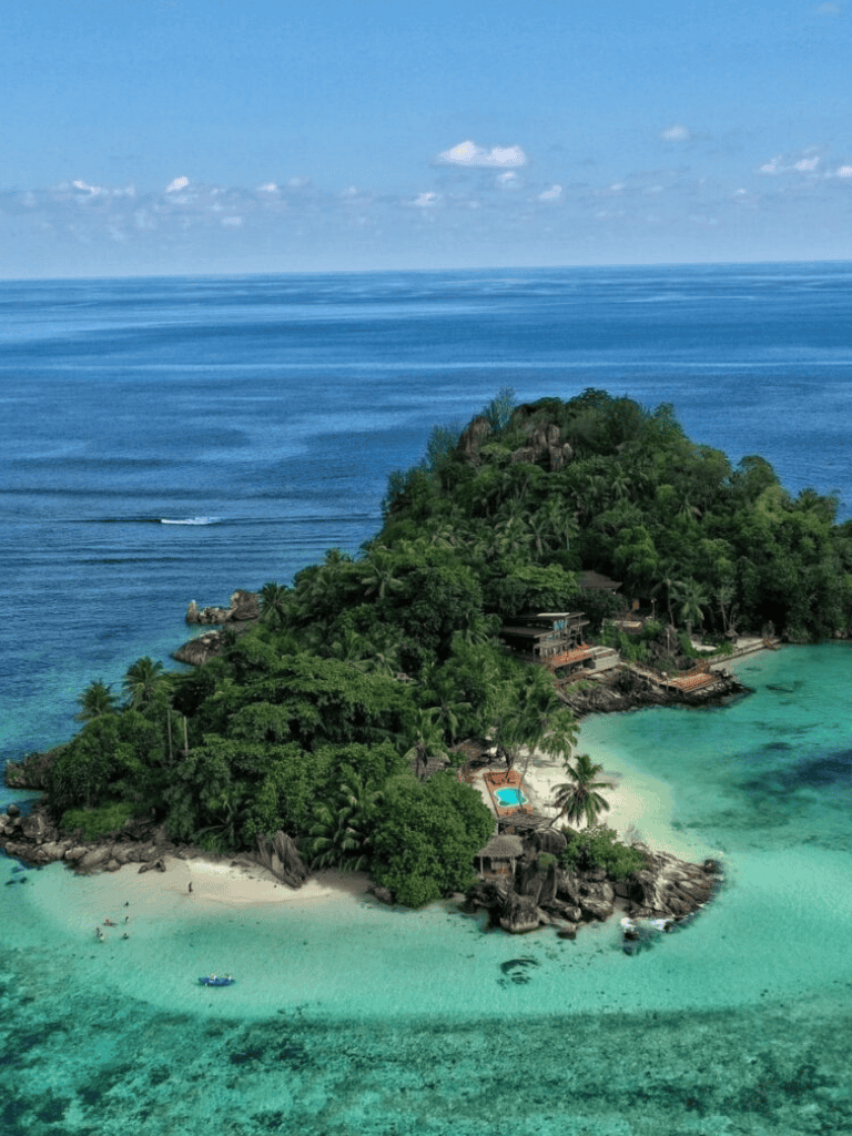 Secluded tropical island with lush greenery and crystal-clear waters, perfect for travel and adventure.