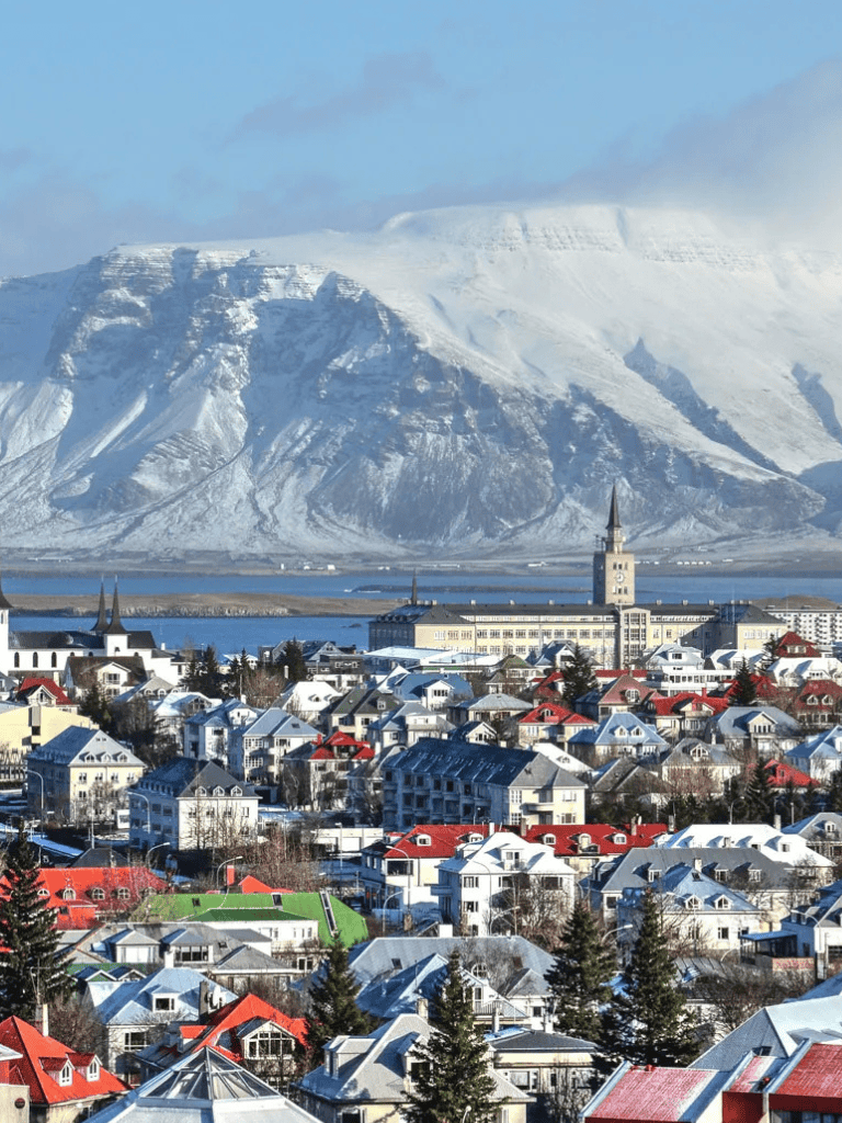 Snowy Reykjavik cityscape with Hallgrímskirkja church and mountain backdrop in Iceland.