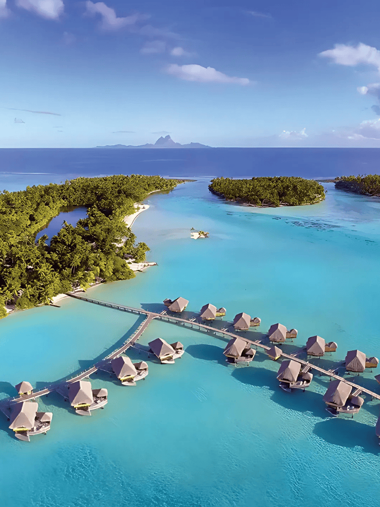 Overwater bungalows on a tropical island resort with turquoise waters and lush greenery.
