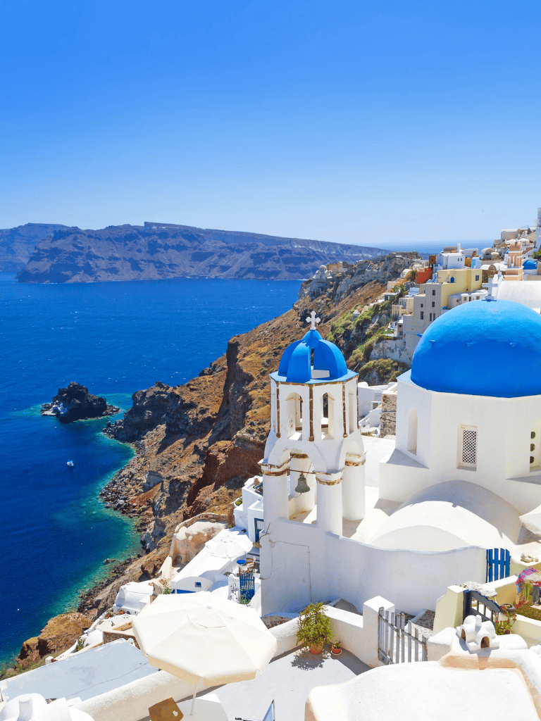 Vibrant blue-domed church in Santorini with Aegean Sea view and white architecture, perfect for travel inspiration.