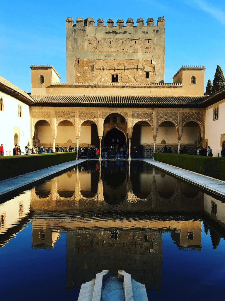 Historical Moroccan fortress with reflective fountain and arched architecture at the entrance.