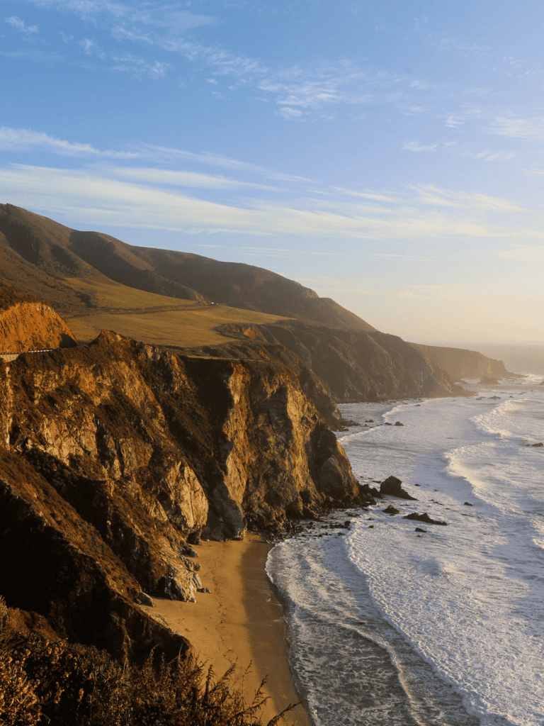 Breathtaking coastal cliffs and sandy beach at sunset in California.