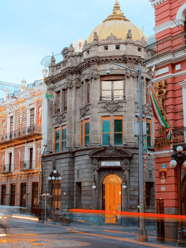 Ornate historic government building with a rounded corner and tall windows, located in a vibrant city street.