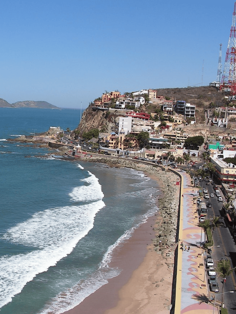 Colorful coastal cityscape with beach, hillside homes, and ocean waves in Tijuana, Mexico.