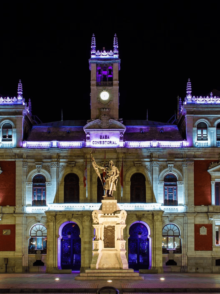 Brightly lit GOVBA ConstruStrial building with statue at night, showing historic architecture.