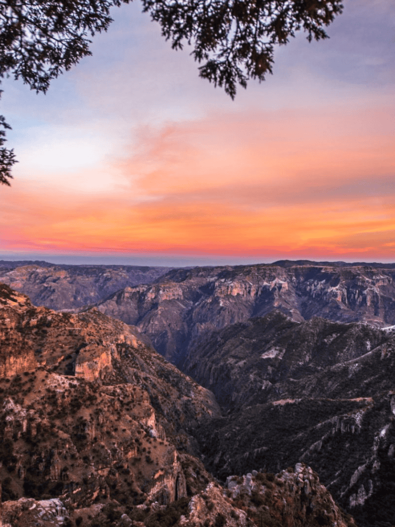 Spectacular canyon view during sunset with colorful sky and rugged cliffs in the background.