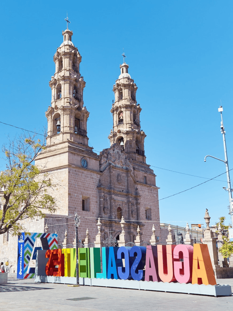 Colorful Acualescali sign in front of historic Mexican church, vibrant Mexico City landmark, cultural tourism destination.