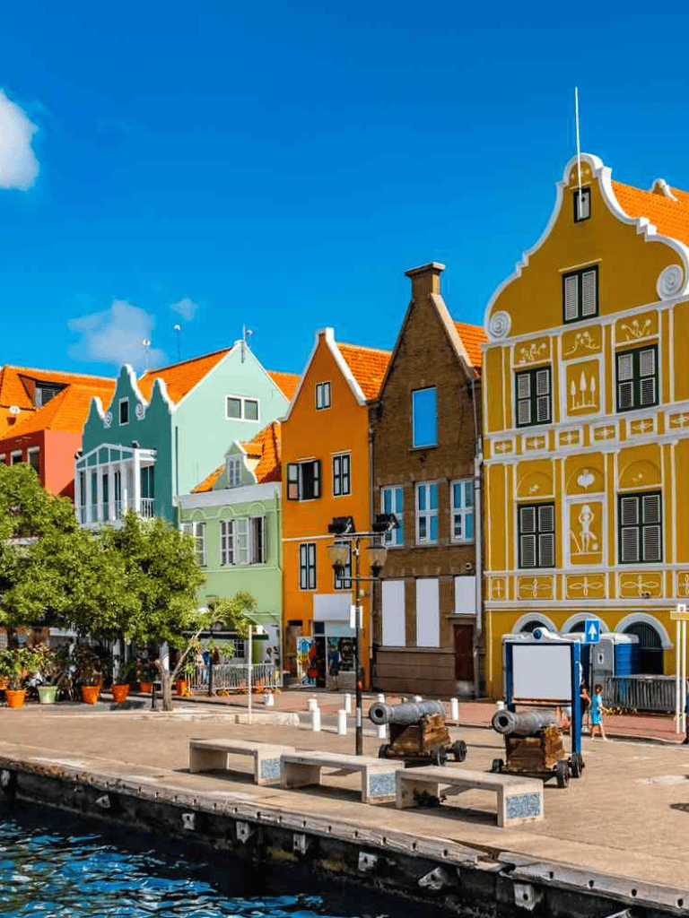 Colorful Dutch houses along a waterfront in Amsterdam, Netherlands, showcasing vibrant architecture and scenic city views.