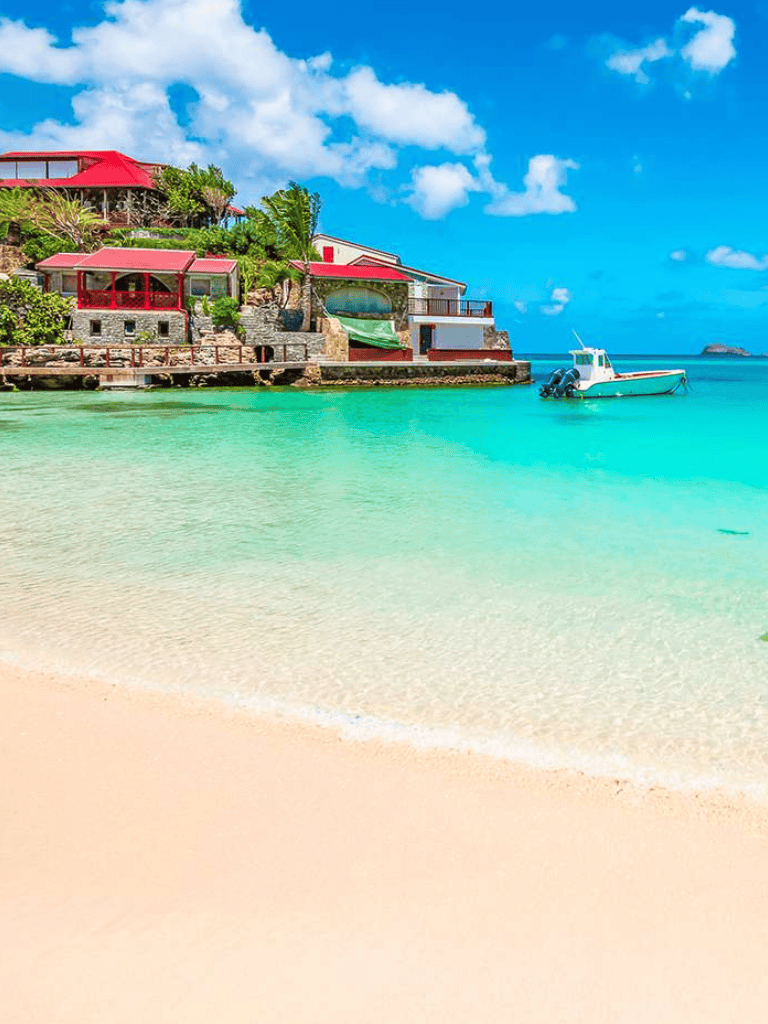 Breathtaking beachfront house with colorful terraces and boats on turquoise water.