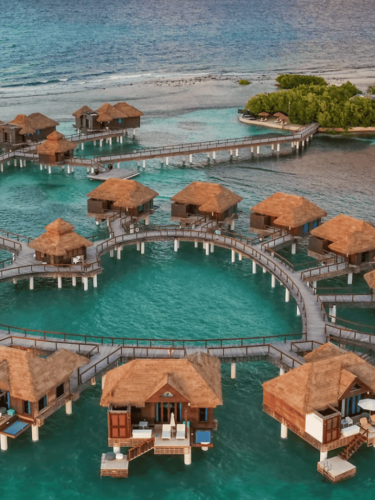 Overwater bungalows with thatched roofs on turquoise lagoon at tropical resort.