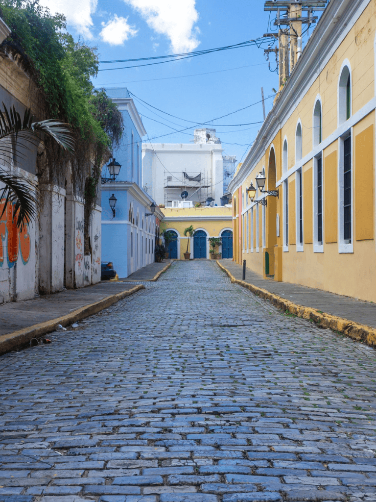 A scenic cobblestone street in colorful historic town with vibrant buildings and clear blue sky.