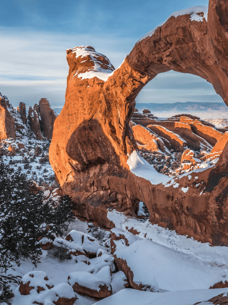 Remarkable red sandstone arch in snowy desert landscape, stunning winter scenery at natural rock formation.