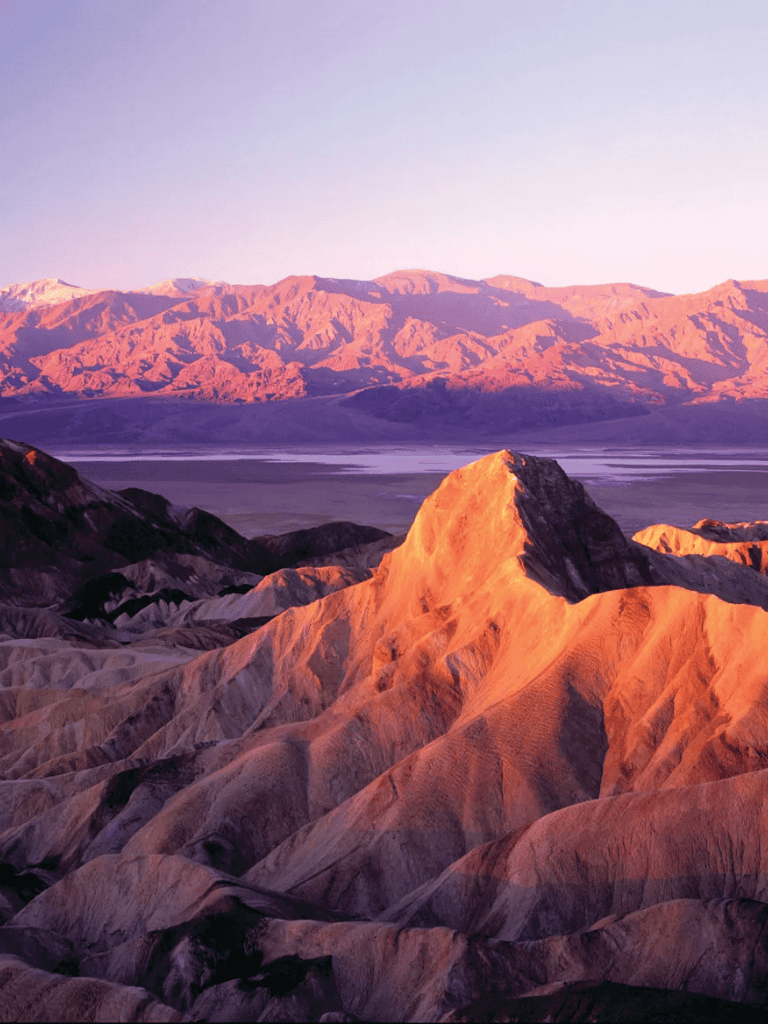 Stunning desert landscape with colorful, layered mountains at sunset.