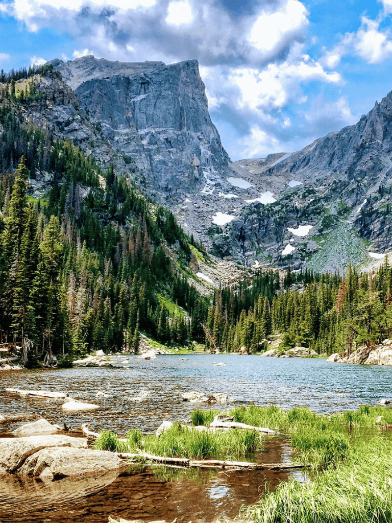 Serene mountain lake surrounded by dense pine forests and towering rocky cliffs in a national park.