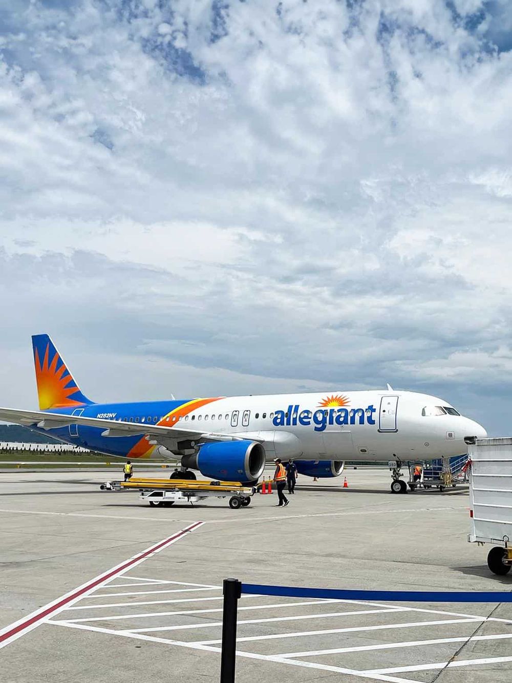 Aircraft at airport with Allegiant Air branding flying in the evening sky.