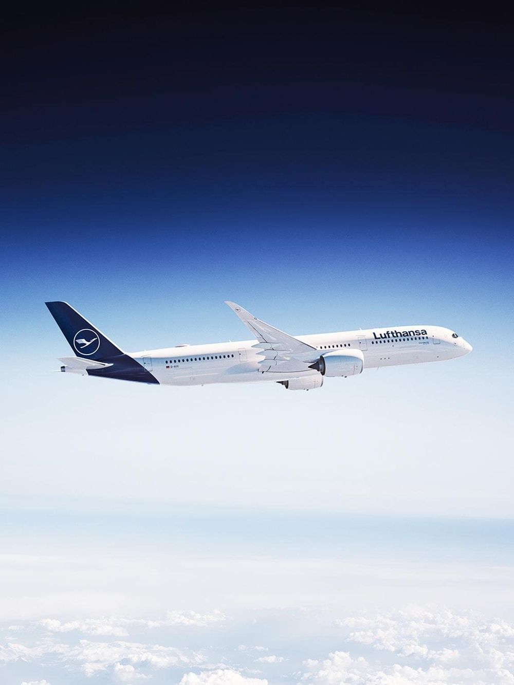 Modern Lufthansa airplane flying high in clear blue sky.