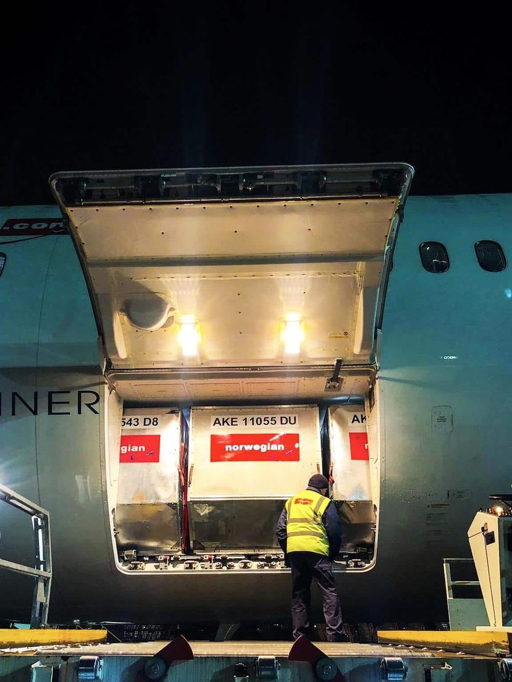 1. Cargo being loaded onto a Norwegian Airlines airplane at night, airport logistics, air freight, and travel logistics.
