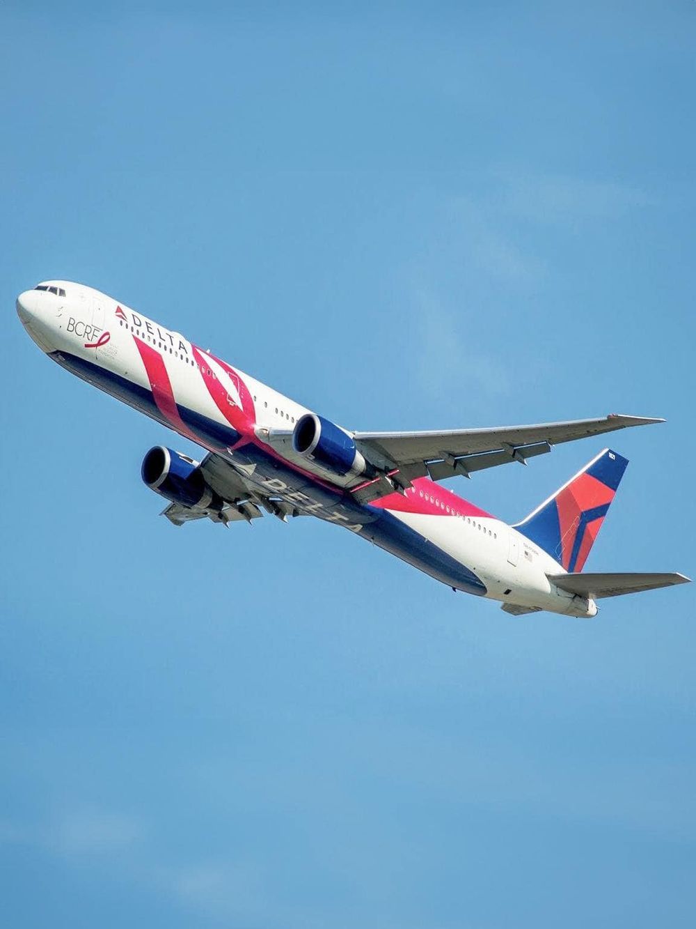 Delta Airlines airplane flying in clear blue sky.