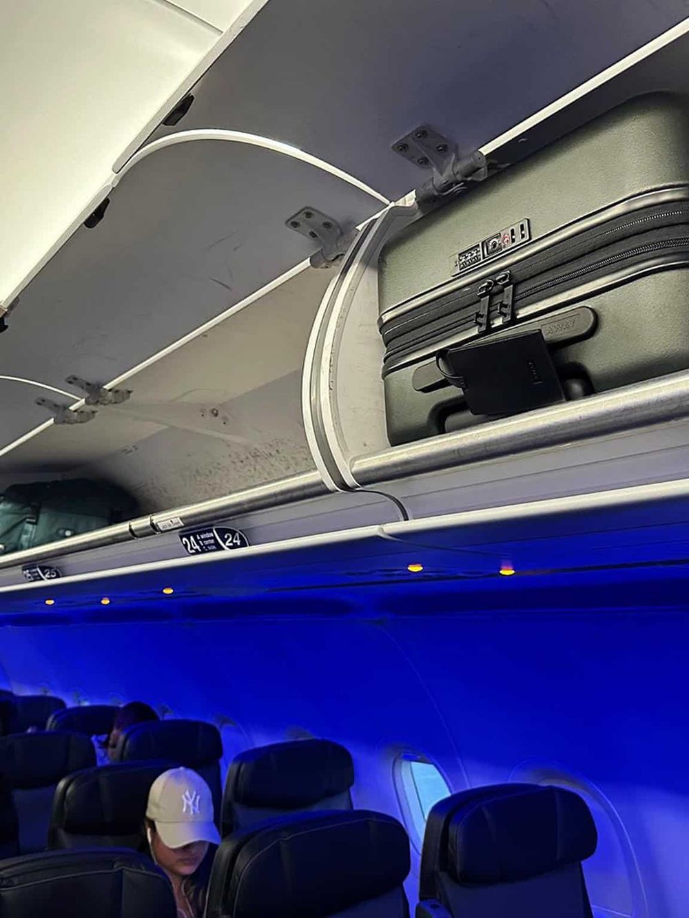 Passenger luggage stored overhead on an airplane with cabin blue lighting, emphasizing flight and travel experience.