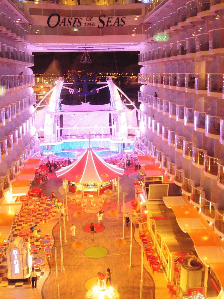 Vibrant Oasis of the Seas cruise ship deck illuminated at night with colorful lighting and entertainment areas.