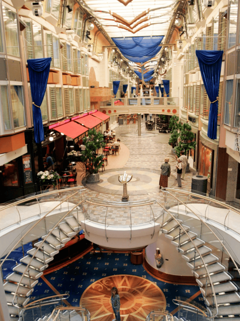 Indoor shopping mall with elegant architecture, blue drapes, and multiple levels of shops and dining areas.