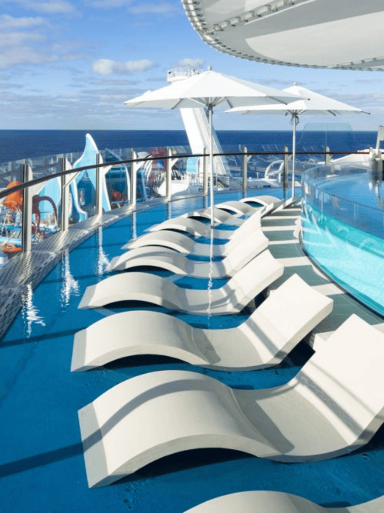 Relaxing poolside loungers on a cruise ship deck with ocean view, perfect for vacation relaxation.