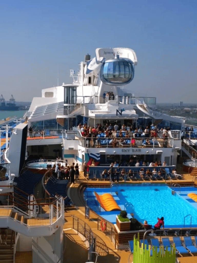 Luxury cruise ship with pool and sky bar, offering scenic ocean views and entertainment.