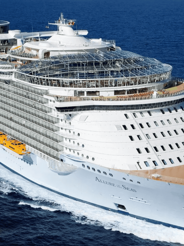 Luxurious cruise ship sailing in open ocean, expansive deck and glass-domed areas.