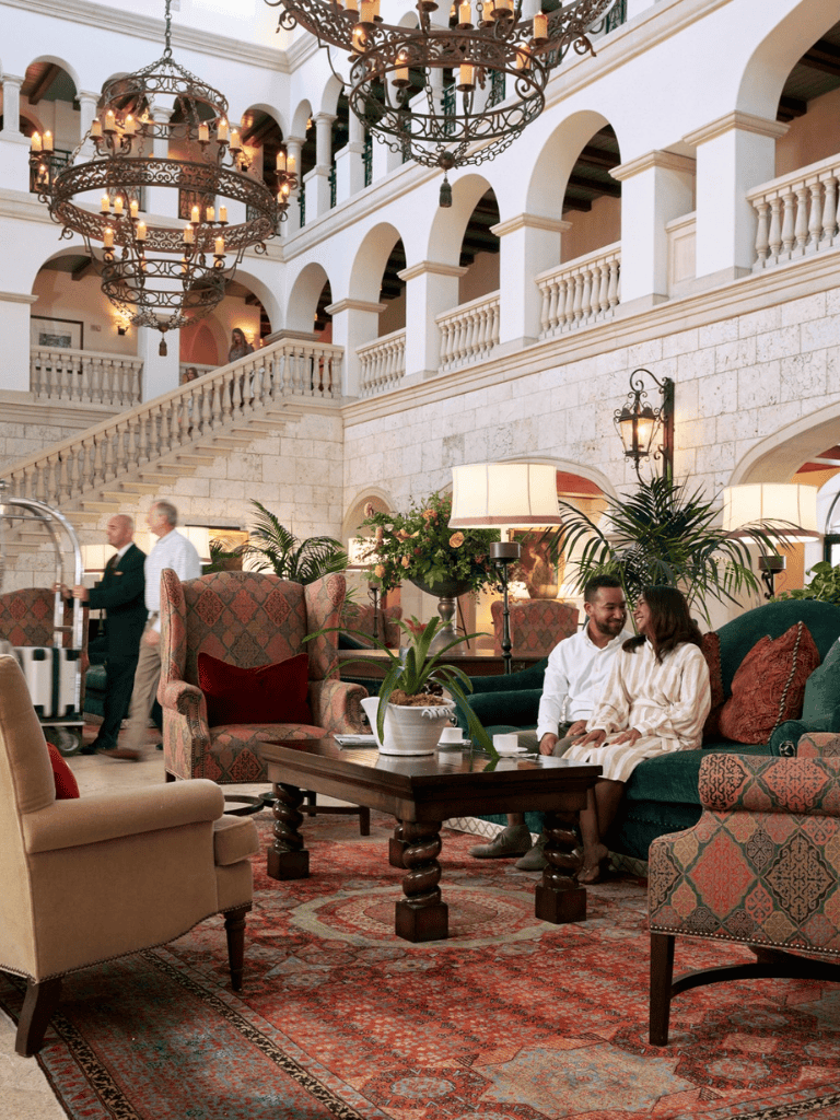 Luxurious hotel lobby with elegant chandeliers, plush seating, and tropical plants, perfect for relaxing and socializing.