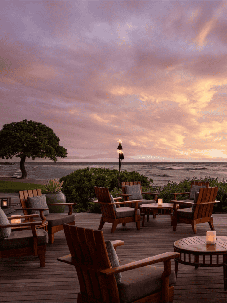 Relaxing oceanfront outdoor seating at sunset with cozy chairs and ambient candles.