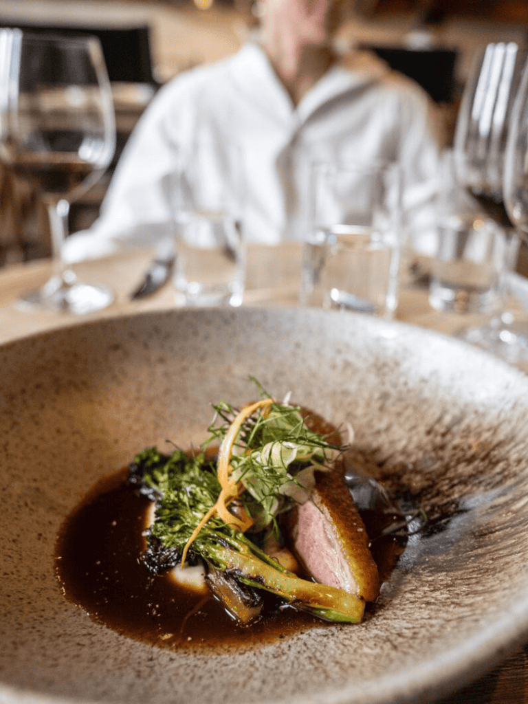Gourmet dish with seared steak and vegetables at QuestForDirections restaurant in a cozy dining setting.