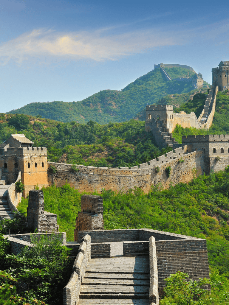Ancient Great Wall of China spanning lush green mountains and historic watchtowers for travel inspiration.