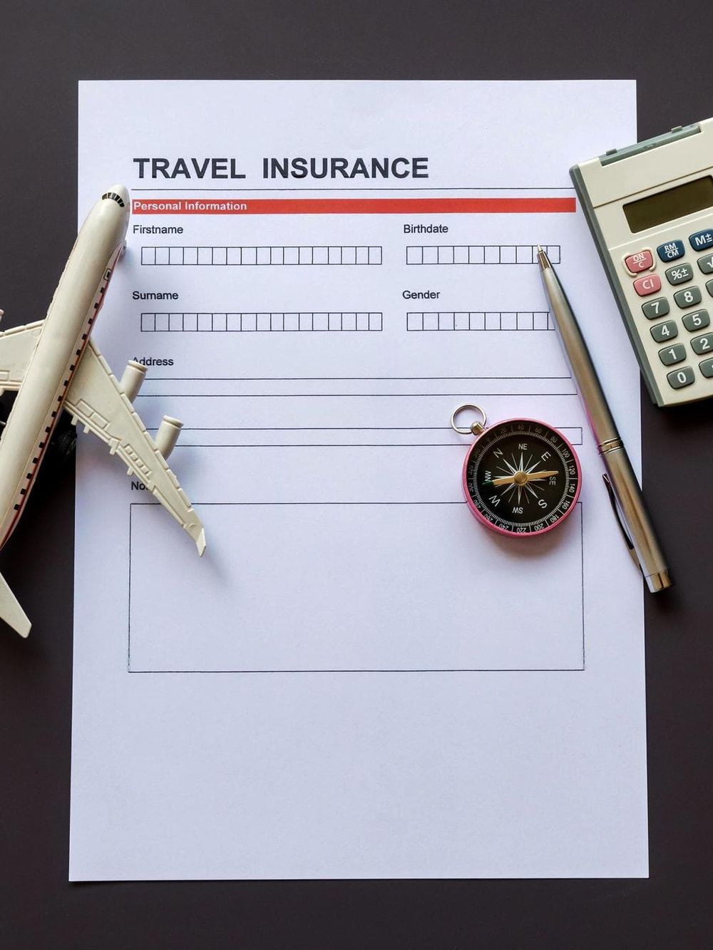 Travel insurance form with airplane model and compass.