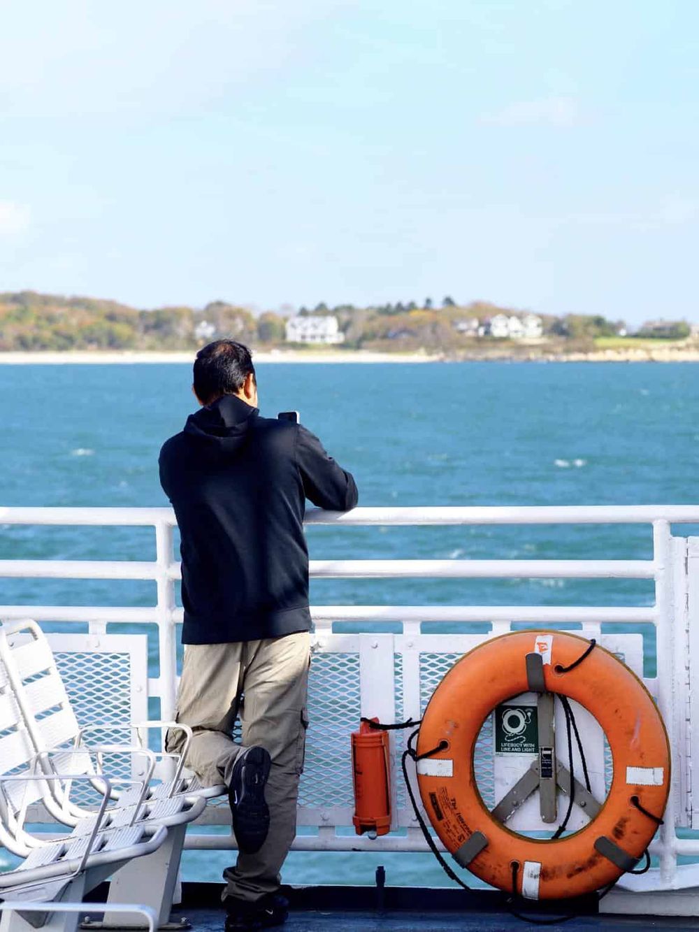 Man taking photo of ocean view from boat deck, travel and adventure scene.