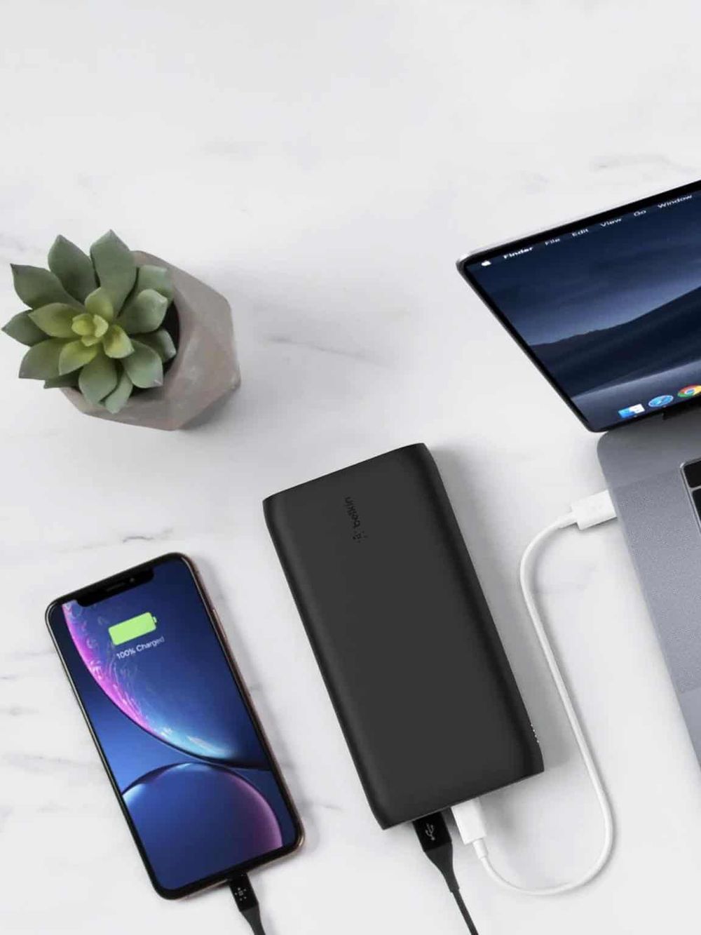 Charging portable power bank for mobile devices on a white desk.