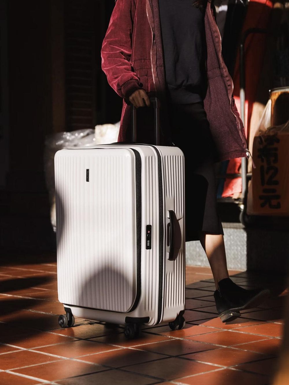 Modern white carry-on suitcase with wheels and digital lock at airport.