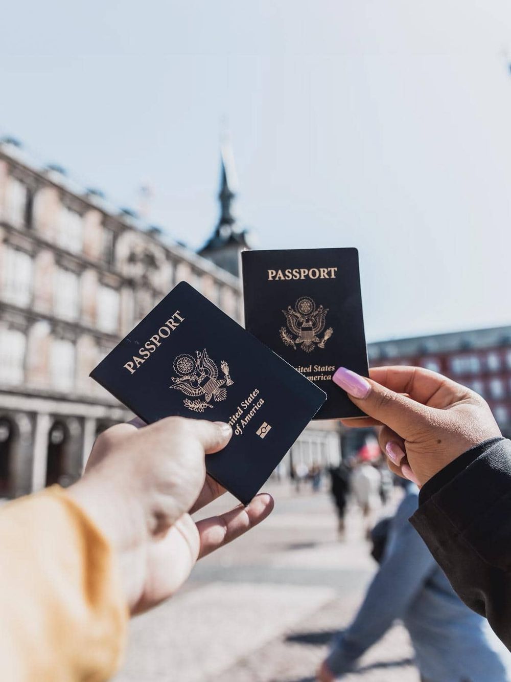 U.S. passports held outdoors in front of historic buildings for international travel.